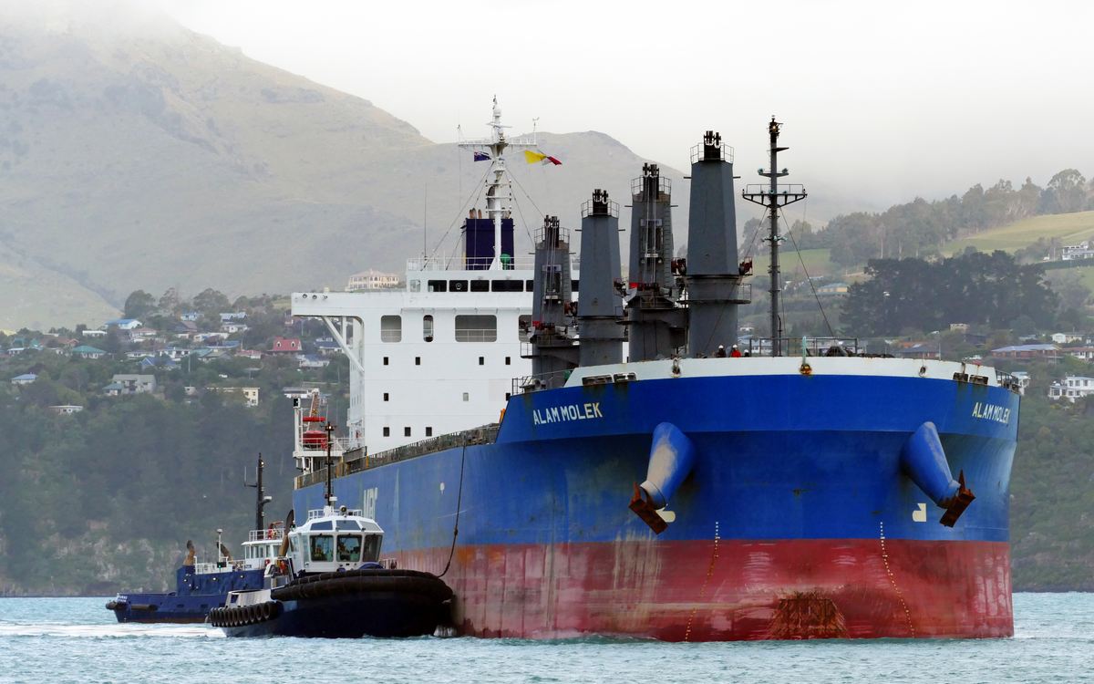 A bulk carrier approaching port with tugs alongside